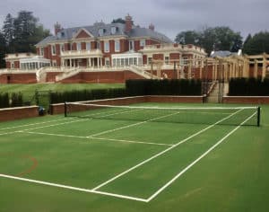 En Tout Cas tennis court fencing.. Obelisk fencing and a retaining wall form the frame to a just-laid Savanna court. Built by En Tout Cas